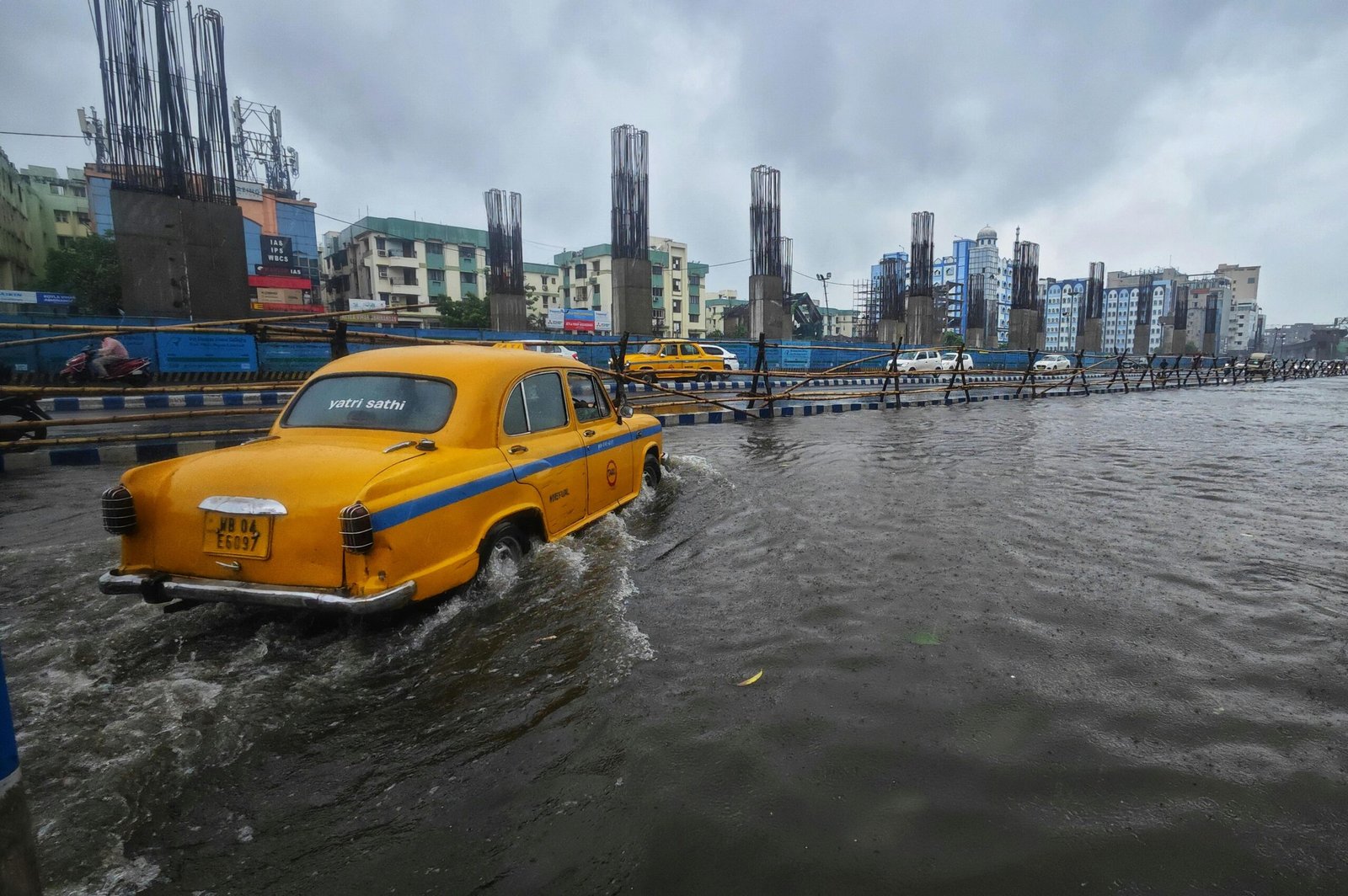 Kolkata street flooded after heavy rain with iconic yellow taxi struggling through water.