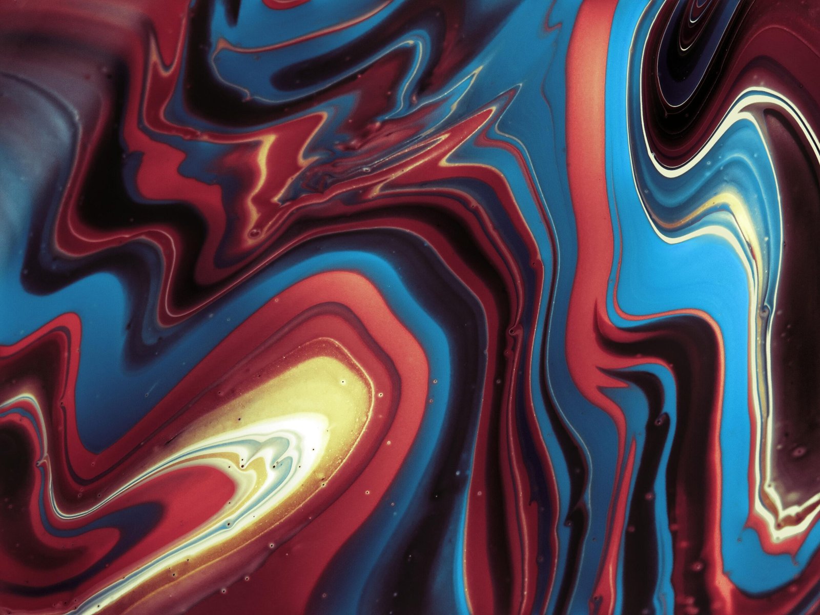 A mesmerizing abstract fluid art piece featuring vibrant blue, red, and yellow swirls in a dynamic composition.